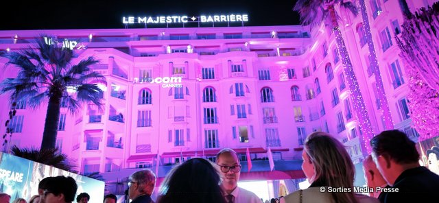 Hôtel Barrière Le Majestic à Cannes illuminé en rose et violet, avec des invités lors du MIPCOM Cannes 2026
